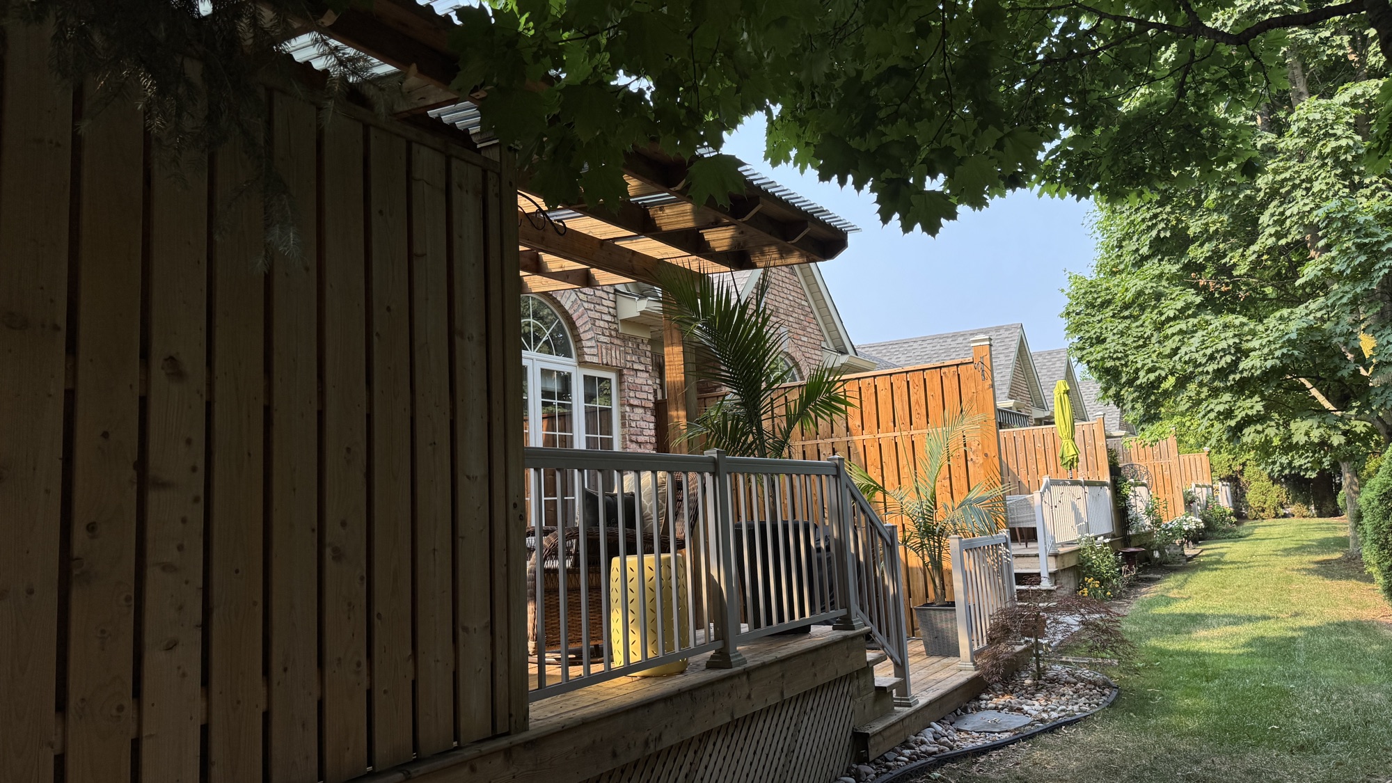 Cedar pergola and covered deck with privacy screen and railing, lit by evening light through the trees