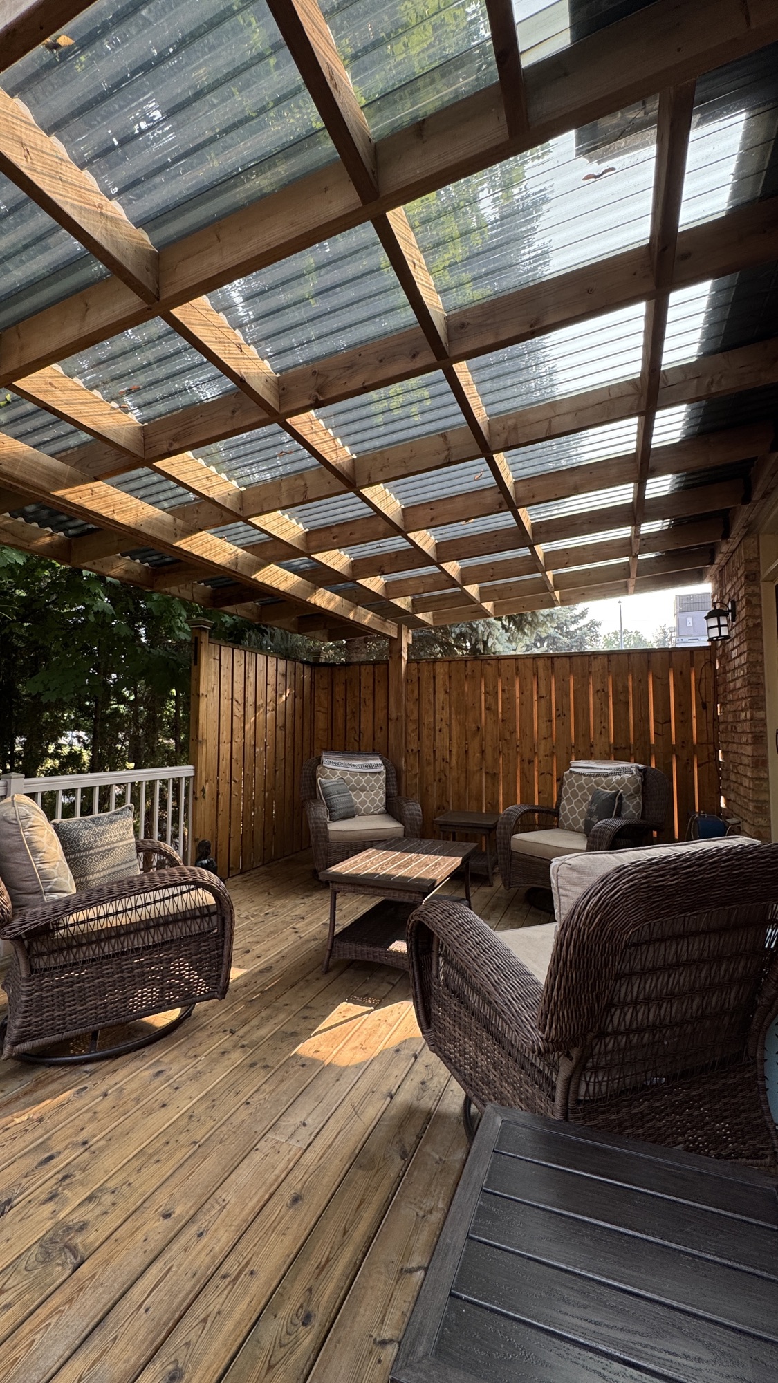 Finished covered cedar deck with wicker lounge furniture beneath a polycarbonate roof