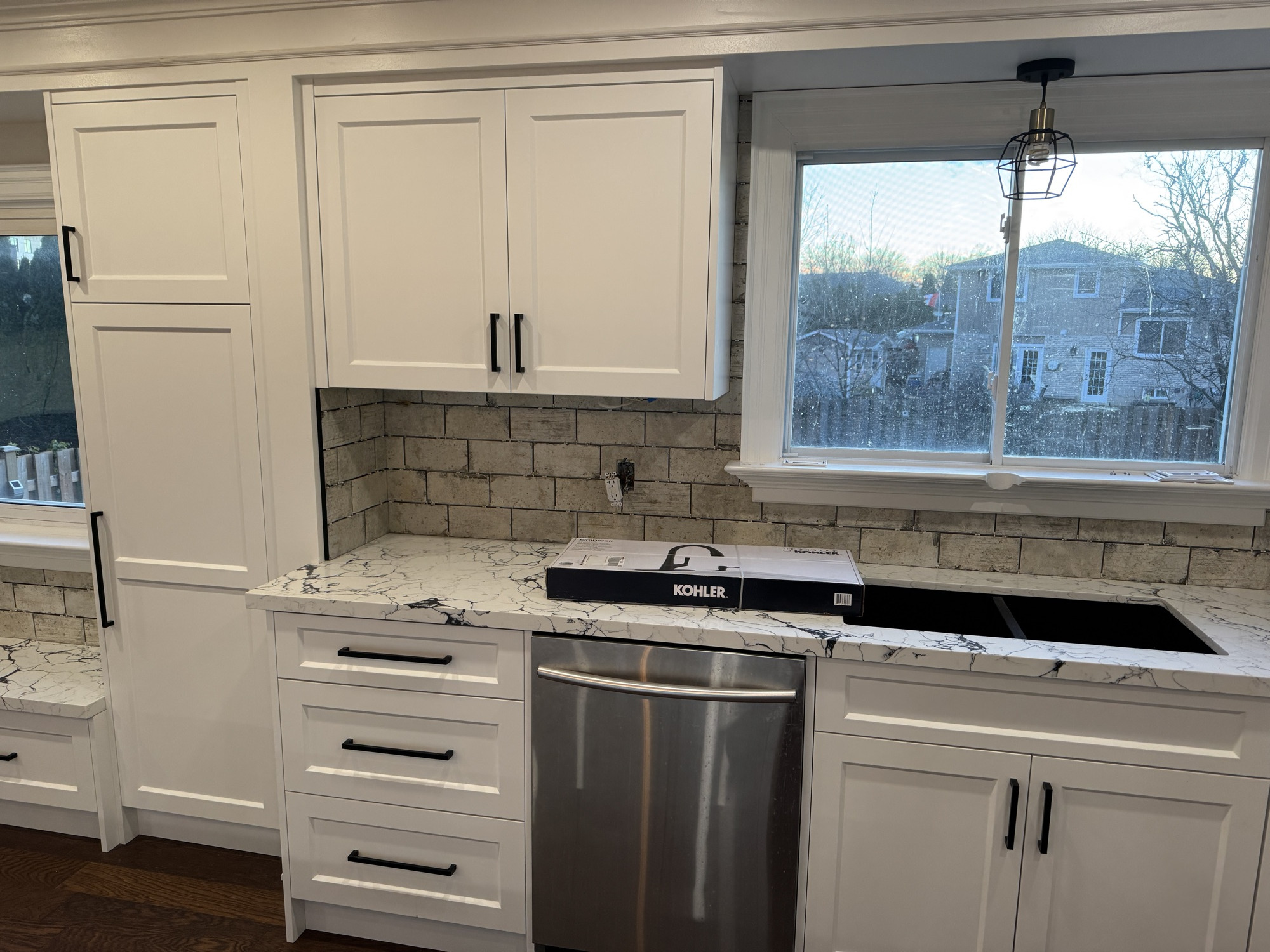 Custom kitchen cabinetry and window detail with an integrated dishwasher and undermount sink