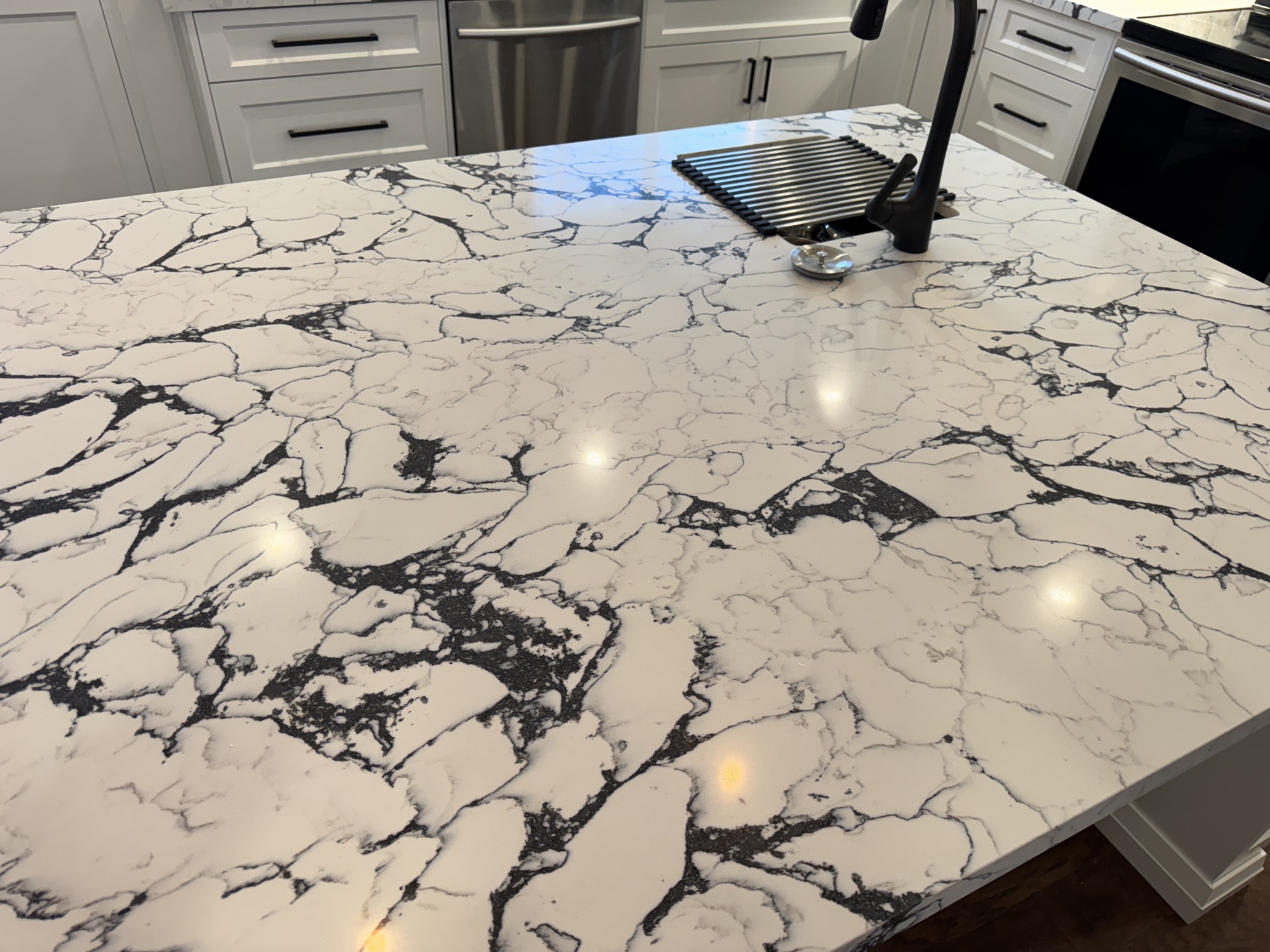 Close detail of the polished marble waterfall countertop with black veining on a custom kitchen island